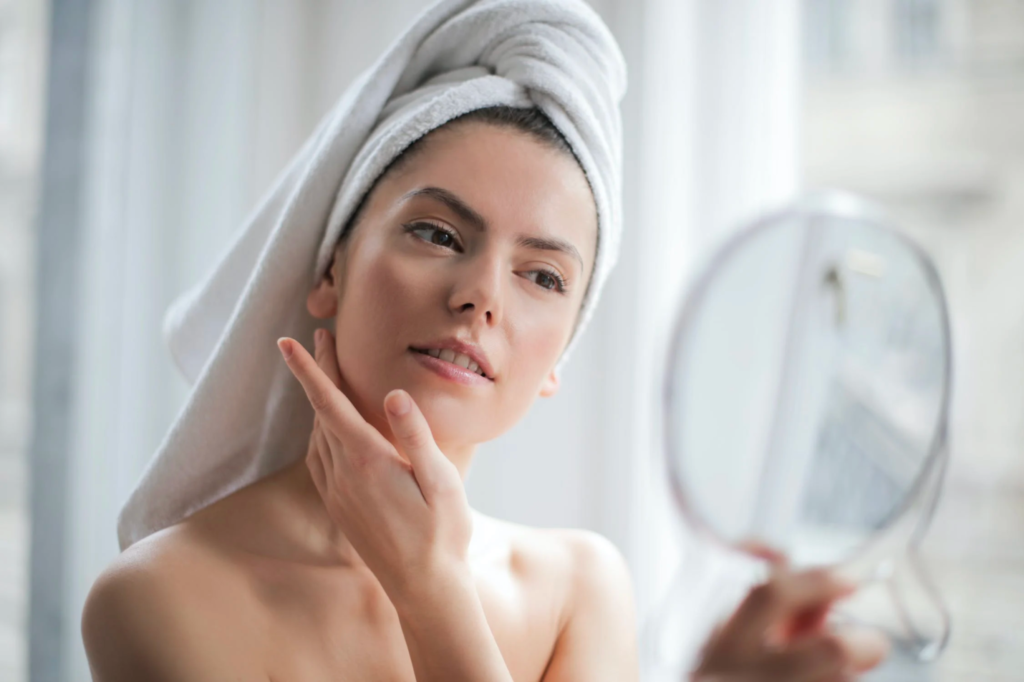 A woman admires her skin while holding up a mirror.